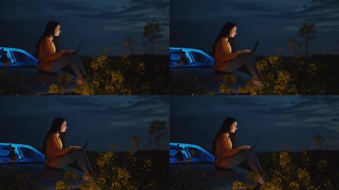 中年黑发女人坐在汽车引擎盖上时使用笔记本电脑，snapdragon花朵在前景中摇曳，慢动作
