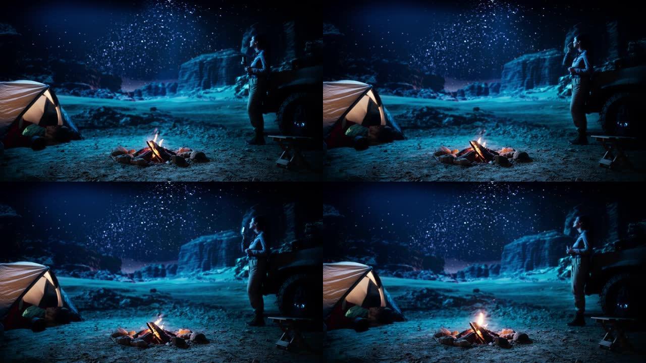 女性旅行者在篝火旁露营时看着夜空。银河系星星的惊人营地景观，有权力的女冒险家热爱自然旅行