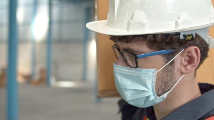SLO MO仓库工人戴着防护口罩，在仓库中肩上扛着纸箱，特写镜头