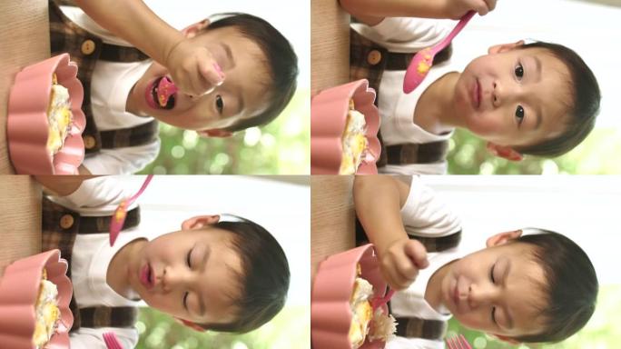 垂直视图亚洲小男孩自己吃饭