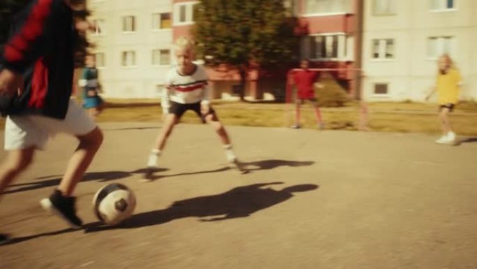 多民族多样的朋友在城市后院外面踢足球。小男孩运球，用球独自传球对手并进球。足球运动员拥抱，庆祝胜利。