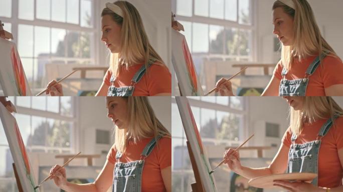 女画家在艺术工作室的画布上创作彩色静物画。艺术家在工作室用画笔画一朵花。创作玫瑰形象的艺术女性