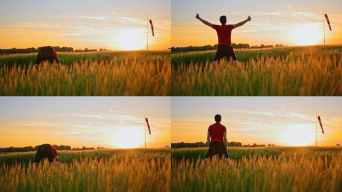 穿着运动服的男运动员手持镜头在高高的草地上练习瑜伽，面对日落，慢动作
