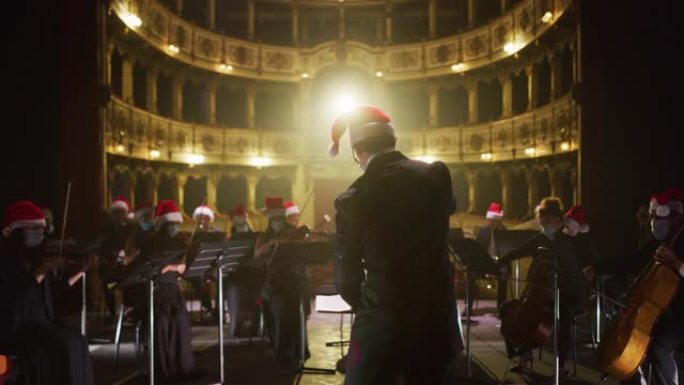 交响乐团的电影镜头，表演者都戴着圣诞老人的帽子，在圣诞节期间在经典剧院和窗帘舞台上演奏小提琴，大提琴