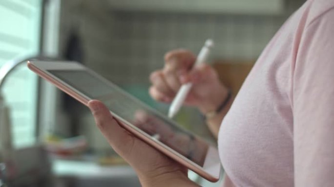 女人在厨房里使用数字平板电脑，特写