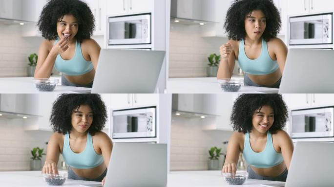 4k视频片段，一名年轻女子在家里吃浆果时使用笔记本电脑