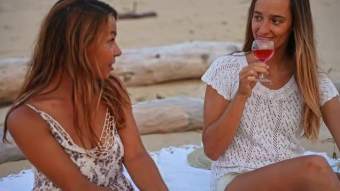 日落时，两名妇女在沙滩上喝玫瑰酒