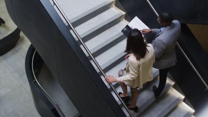 多元化的商人和女商人在现代办公室的楼梯下交谈和交谈