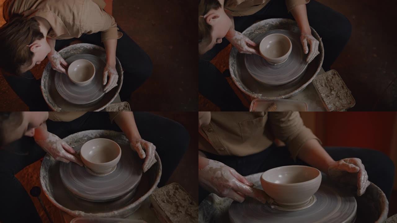 SLO MO专业女波特在陶器工作室用粘土模制杯子