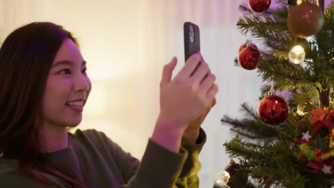 微笑的年轻女子在新年前在客厅装饰圣诞树。