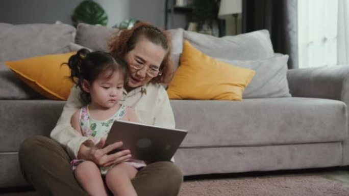 祖母在家和孙女玩数字平板电脑。获得新的自我价值感，转移知识的机会以及成为榜样的能力
