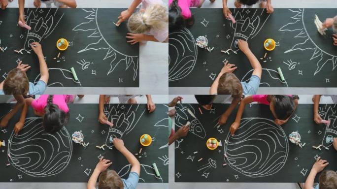 在儿童教室里用粉笔和黑板从上面进行创意，绘画和有趣的活动。一群不同的孩子一起学习，并在课堂上创建一个