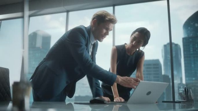 成功的公司首席执行官和投资经理的肖像，站在城市办公室时使用笔记本电脑交谈。两个商人用拳头庆祝成功的交