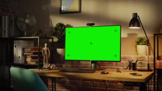 放大现代个人电脑显示器，色度键绿屏显示站在舒适的家庭办公室的桌子上。室内设计师的客厅，品味和创意氛围