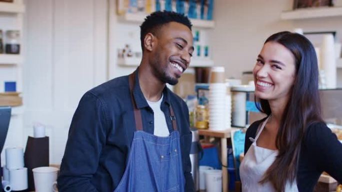 微笑的夫妇一起站在柜台后面经营咖啡店的肖像