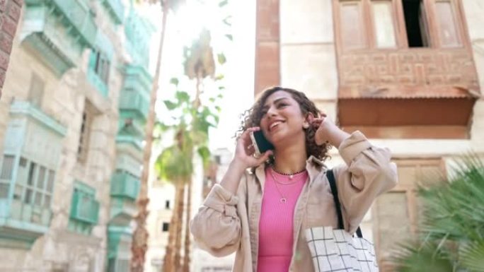 微笑的中东妇女在户外使用智能手机