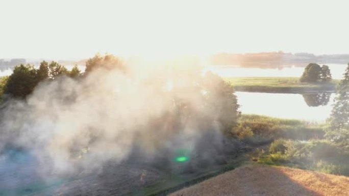 烟雾从篝火升起，在惊人的夏季日出湖岸，美丽的镜头耀眼自然背景风景。