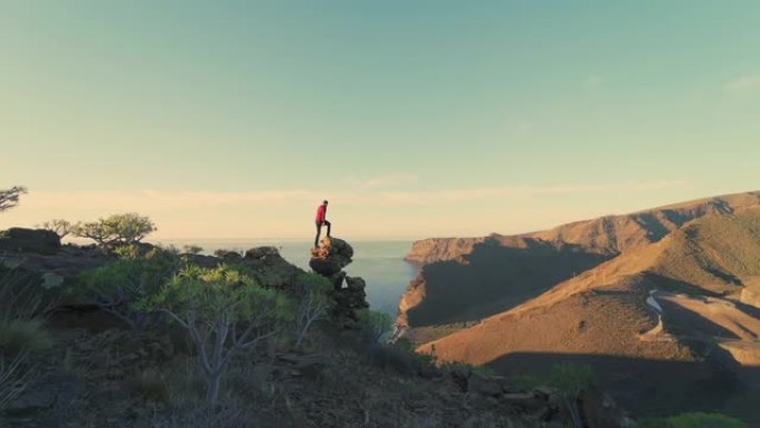 西班牙加那利群岛戈梅拉景观中的SLO MO WS男子跳上岩石