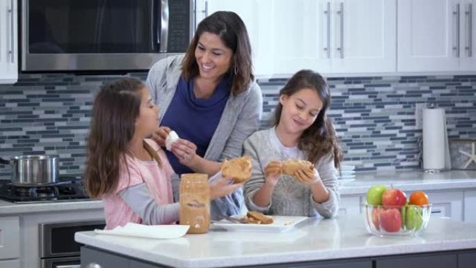 西班牙裔母亲，双胞胎女孩吃花生酱三明治