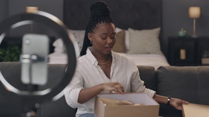 4k视频片段，一名年轻女子坐在公寓的卧室里，使用手机和照明环在新的高跟鞋上拍摄