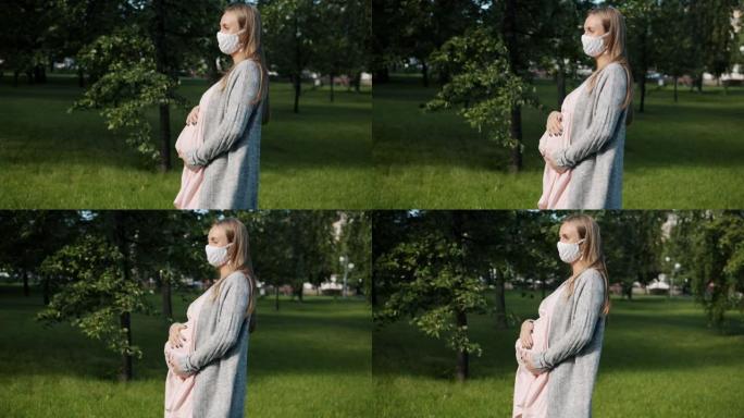 年轻的孕妇在大流行期间戴着医用口罩站在城市公园的户外