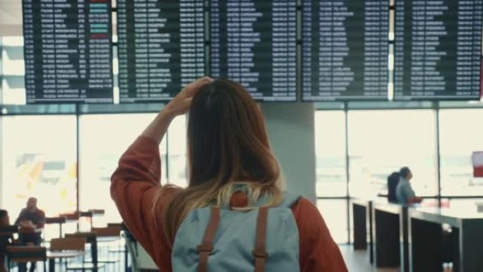 后视年轻的旅游妇女，用智能手机检查时间表板和离开的医疗面具背包。
