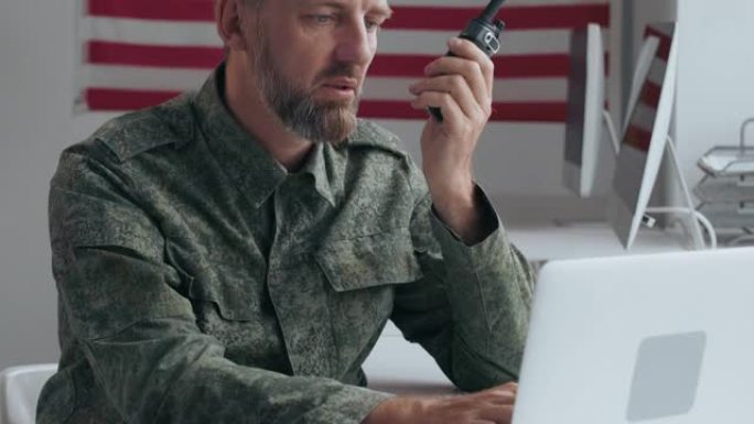 陆军军官使用笔记本电脑和对讲机通话