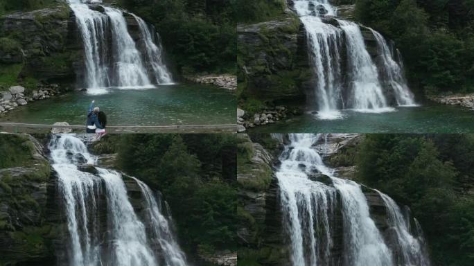 一对夫妇在俯瞰瑞士瀑布的桥上拍摄的4k无人机镜头