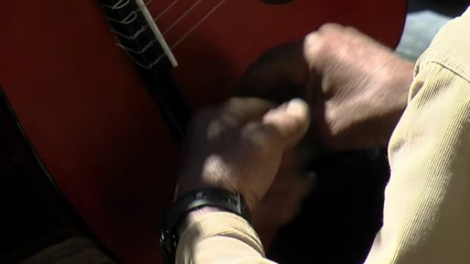 一名老人在阿根廷巴塔哥尼亚的内乌肯 (Neuquen) 演奏时敲打吉他的身体。特写。