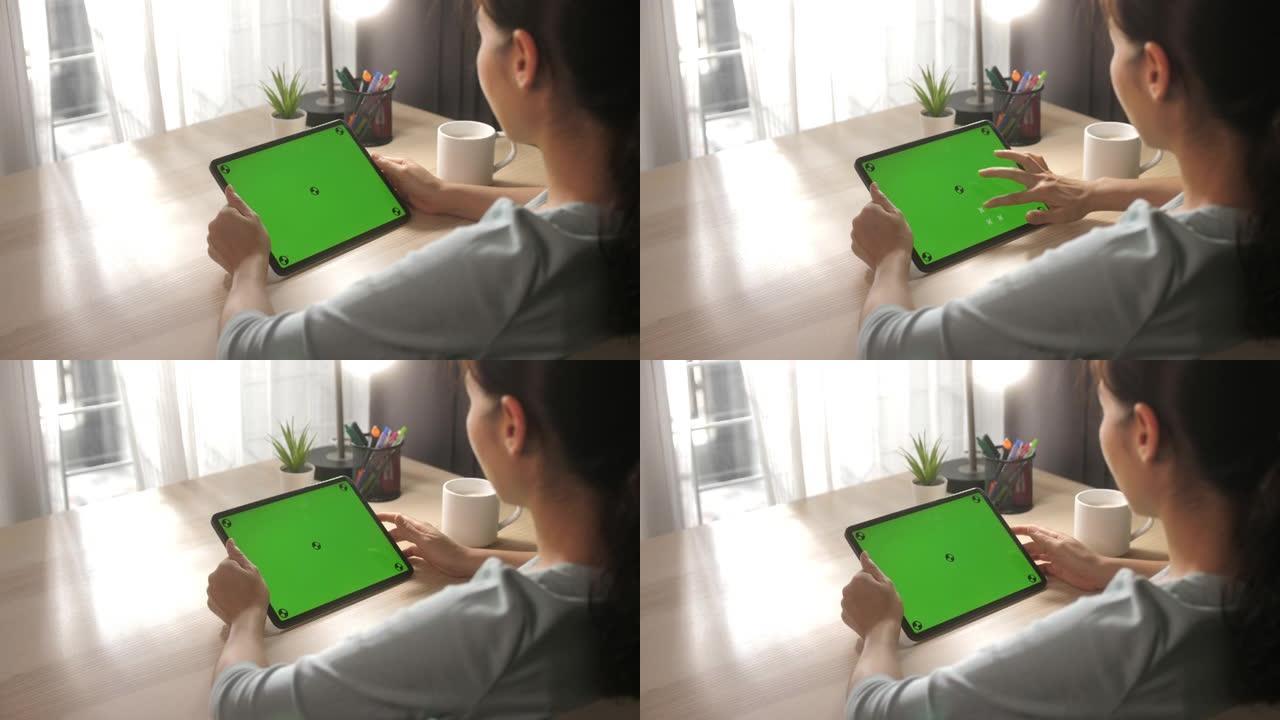 年轻女子在风景模式下使用带有绿色屏幕的数字平板电脑