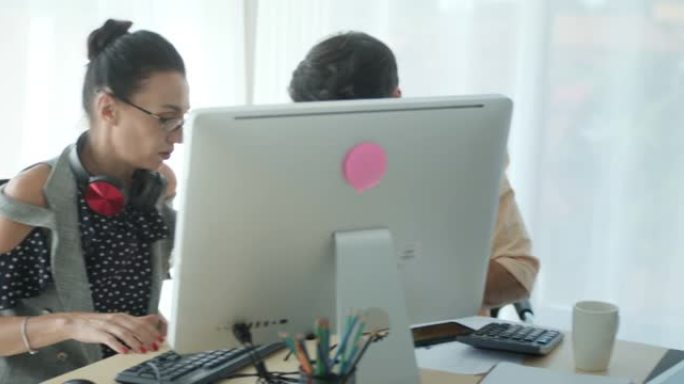 SLO MO同事小组使用计算机并在现代办公室中进行讨论