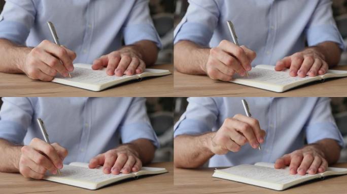 男人坐在桌子上，拿着笔在个人日记中写字