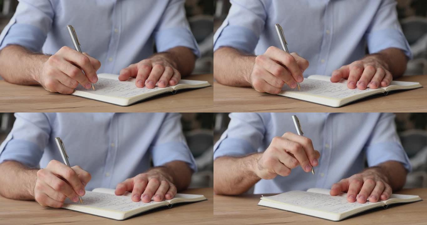 男人坐在桌子上，拿着笔在个人日记中写字