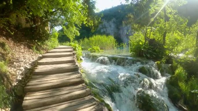 镜头耀斑: 木制台阶通向Plitvice阳光普照的瀑布的顶部。