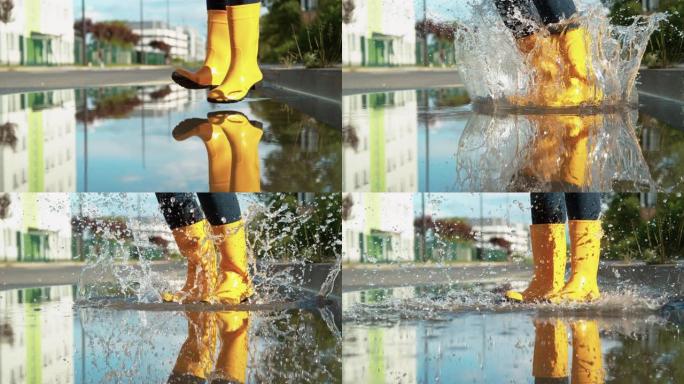 特写: 穿着黄色雨靴的无忧无虑的年轻女子跳进大水坑。