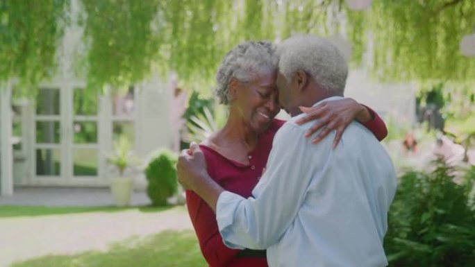 充满爱心的高级夫妇站在家里的花园里，退休后拥抱
