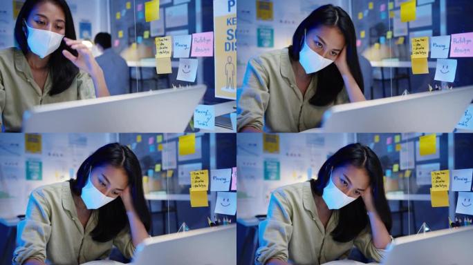 自由职业者亚洲妇女在新的正常办公室使用笔记本电脑努力工作戴口罩。