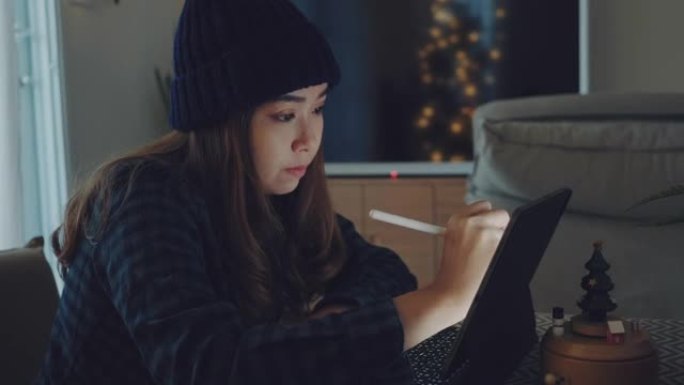 圣诞节期间，女商人用她的数字平板电脑在家工作。