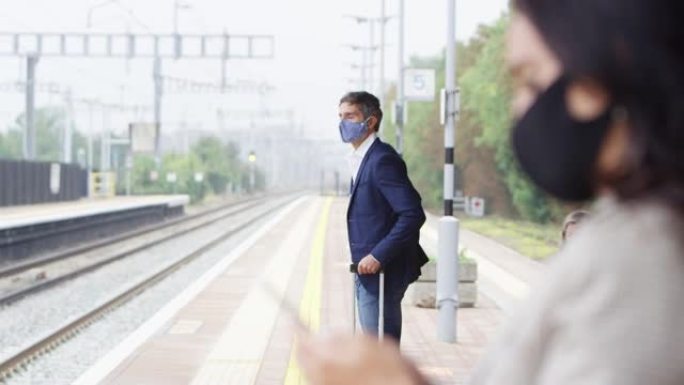 大流行期间戴着PPE口罩的铁路站台上的商务通勤者
