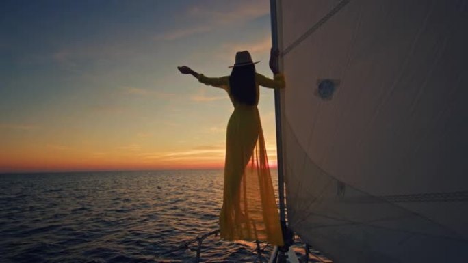 穿着黄色长裙的SLO MO女人享受日落时的风帆