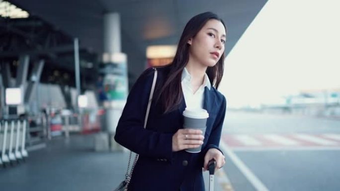 投资者妇女在机场出发区手持咖啡杯等候机场接驳巴士