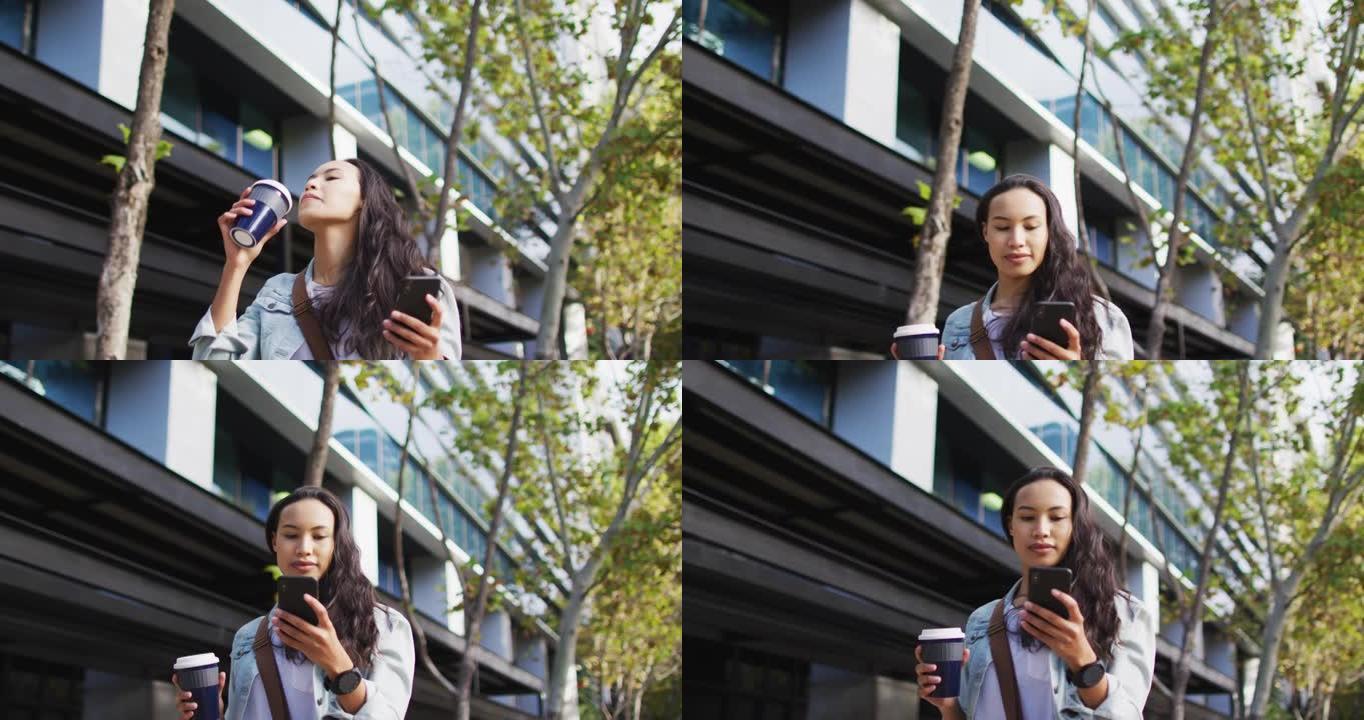 亚洲妇女使用智能手机走路并喝外卖咖啡