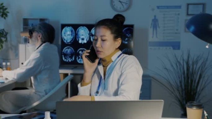 亚洲女医生在黑暗的医院里在手机上聊天并在晚上看肺部CT图像
