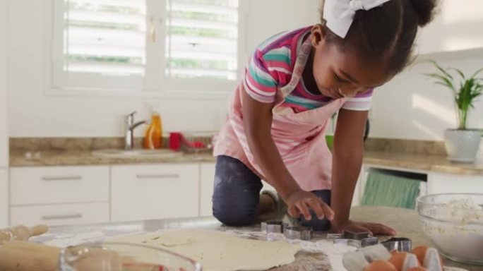 快乐的非洲裔美国女孩在厨房里使用饼干切割器