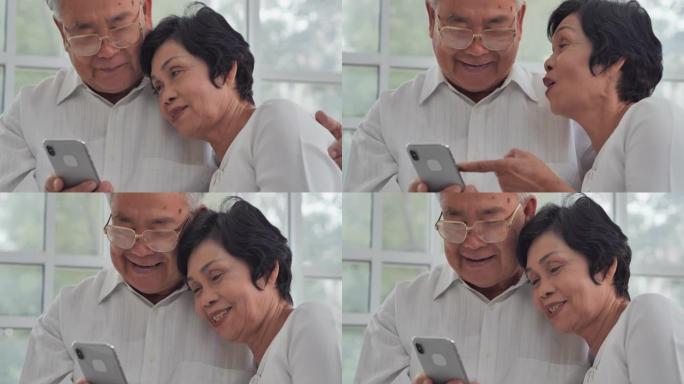 60-65岁的亚洲老年人夫妇在使用智能手机和视频会议技术进行社交距离时，在家中通过视频会议与医护人员