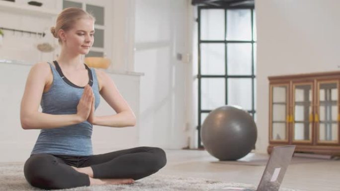 女人在家里通过电脑上的瑜伽课在线练习瑜伽课