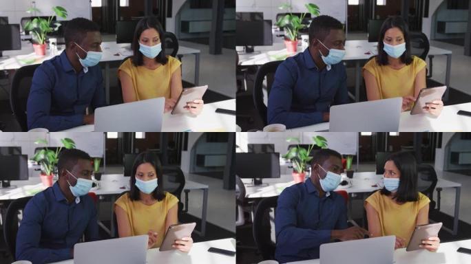 使用平板电脑坐在办公桌前戴着口罩的男女商业同事