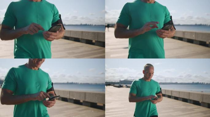 一个穿着绿松石t恤的金发斯堪的纳维亚男子正在路堤上行走，微笑着在手机中阅读一些漂亮的信息