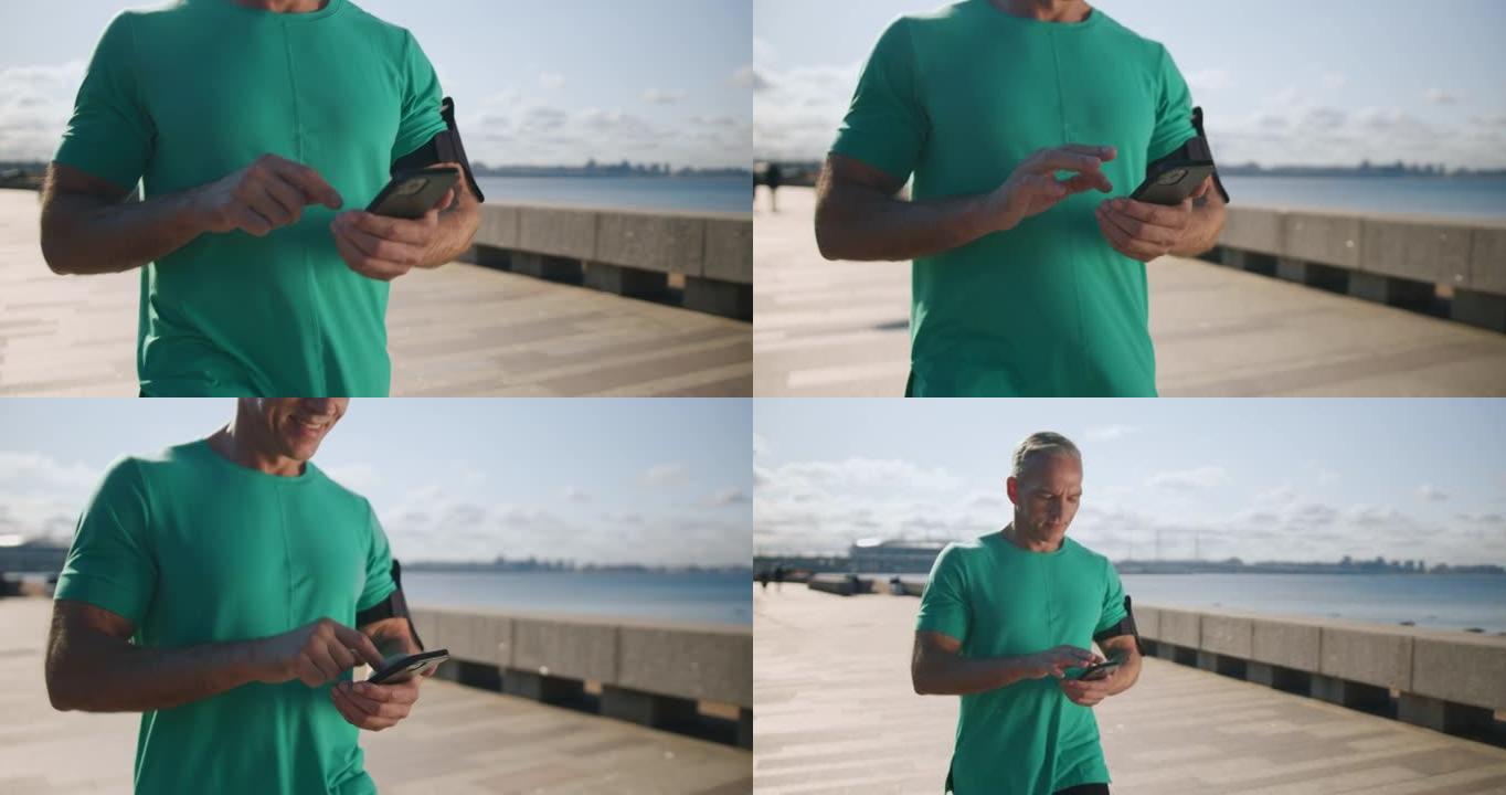 一个穿着绿松石t恤的金发斯堪的纳维亚男子正在路堤上行走，微笑着在手机中阅读一些漂亮的信息