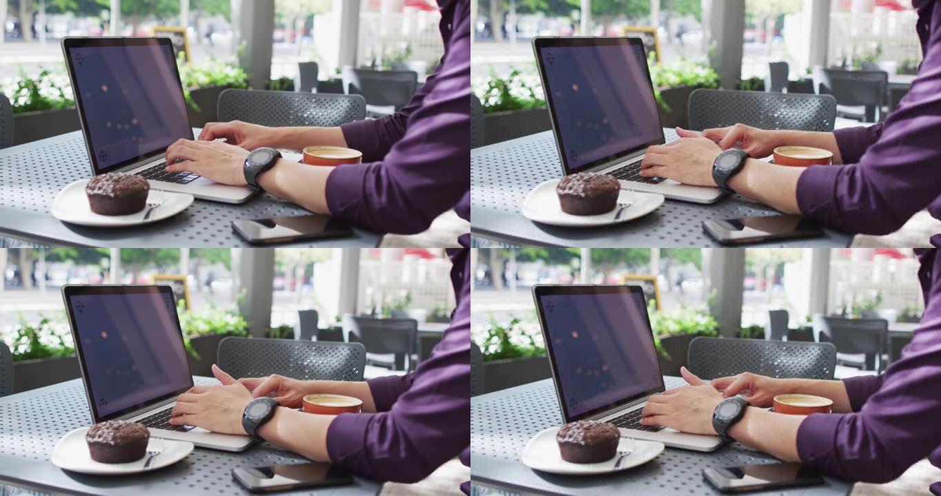 亚洲男子坐在咖啡馆时在笔记本电脑上打字，并带有复印空间